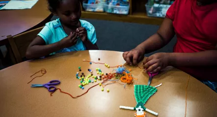 Youth creating with string and beads.